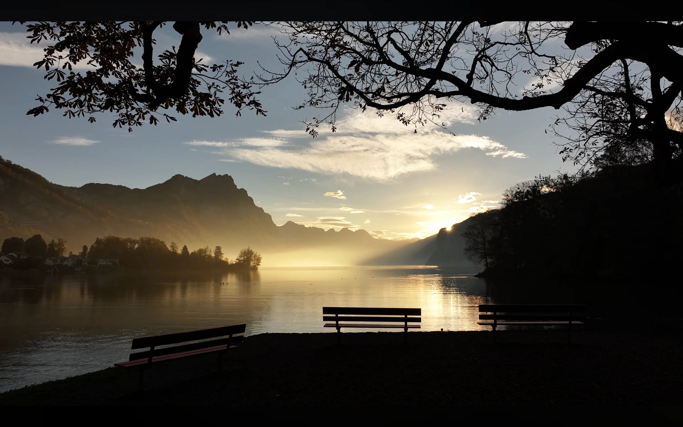 Sonnenaufgang über einem See mit Bergsilhouette, Filmstill aus dem Imagefilm der lumisol GmbH.